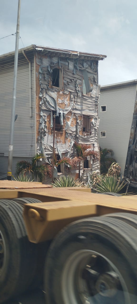 A residential building with a severely burned and warped exterior facade.